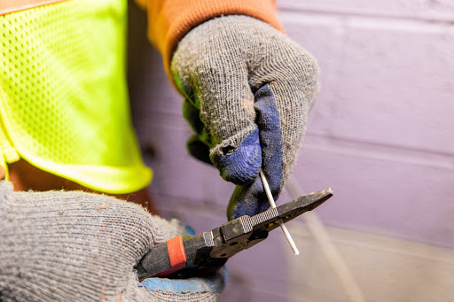 Image of hands with electric gloves, pliers and a wire